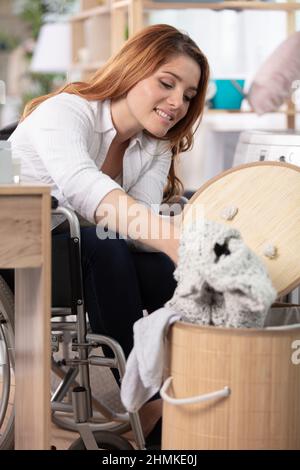 Glückliche Frau im Rollstuhl, die schmutzige Tücher nahm Stockfoto