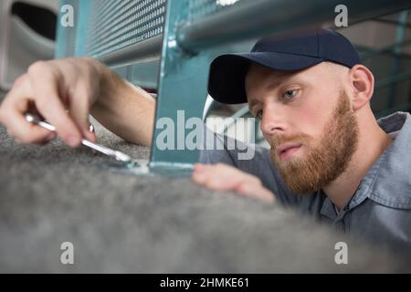 Nahaufnahme eines Teppichmonteppichers Hand Installation grauen Teppich Schraubendreher Stockfoto