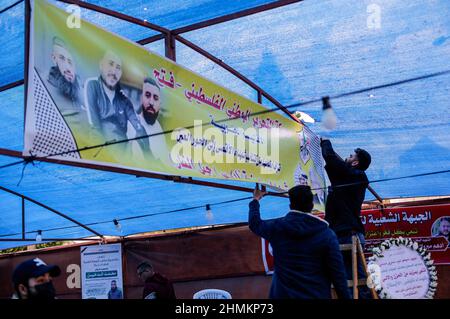 Gaza-Stadt, Palästina. 09th. Februar 2022. Palästinenser hängen ein Transparent, auf dem der Verstorbene während der Beerdigung dargestellt ist. In Gaza-Stadt trauern drei Palästinenser, die in Nablus getötet wurden. Israelische Truppen töteten am 8th. Februar bei einem Tagesangriff in der Stadt Nablus im Westjordanland drei Palästinenser. Kredit: SOPA Images Limited/Alamy Live Nachrichten Stockfoto