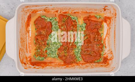 Rezept für Spinat-Lasagne. Schicht aus Lsagna-Nudeln, Schicht aus Spinatmischung und Schicht aus Marinara-Sauce. Lasagne zusammenbauen, Vorbereitungsprozess Stockfoto