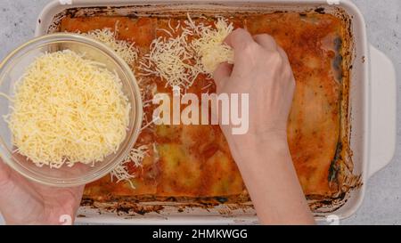 Lasagne mit Parmesankäse überbacken. Schritt für Schritt Spinat Lasagne Rezept, Frau Hände, flach legen Stockfoto