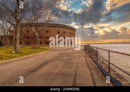 Historisches Backsteinfort Castle Williams auf Governors Island, das den Hudson River in New York mit einem atemberaubenden Sonnenuntergang bewacht Stockfoto