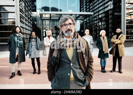 Business-Chef, der sich von einer Business-People-Gruppe absticht, während er im Finanzdistrikt zusammensteht. Stockfoto