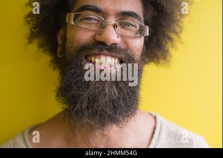 Junger Mann mit Afro-Schuss gegen gelbe Wand Stockfoto
