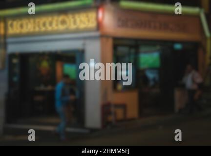 Verschwommener abstrakter Hintergrund von Menschen, die nachts auf der Straße spazieren Stockfoto