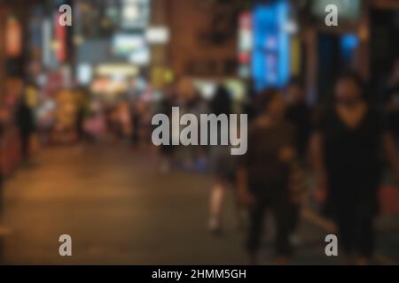 Verschwommener abstrakter Hintergrund von Menschen, die nachts auf der Straße spazieren Stockfoto