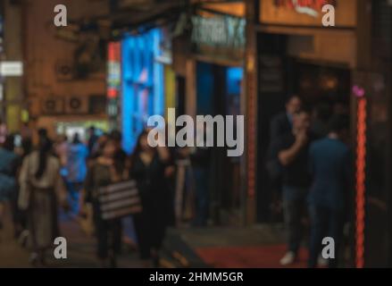 Verschwommener abstrakter Hintergrund von Menschen, die nachts auf der Straße spazieren Stockfoto