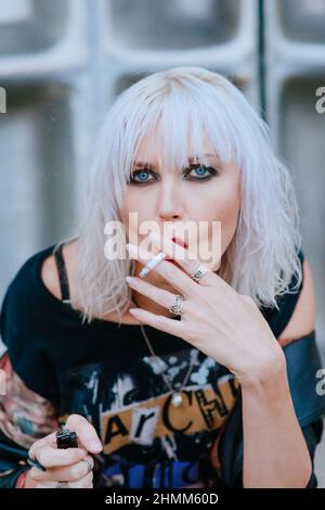 Porträt der stilvollen blonden Grunge junge Frau mit Make-up Rauchen Zigarette Stockfoto