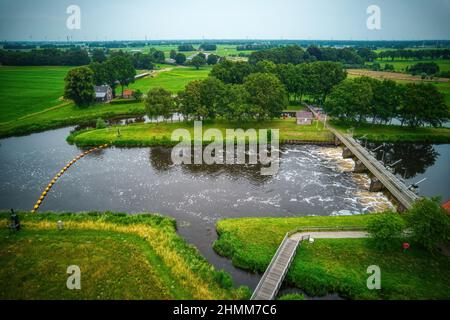 Drohnenansicht des Flusses Vecht, grünes Gras, Bäume, schöner blauer Himmel und Radweg durch das Vecht-Tal. Brücke und Wehr im Fluss. Dalfsen N Stockfoto