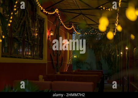 Weihnachtsdekorationen in der Bar. Gelbe Girlanden an den Wänden. Frohes neues Jahr. Weihnachtslichter im Restaurant, Lampen. Hochwertiges Foto Stockfoto