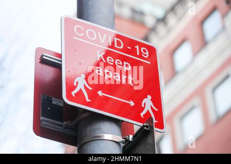 Straßenschilder, um zu versuchen, die Ausbreitung von COVID-19 zu kontrollieren, erinnern die Menschen an soziale Distanz aufgrund der Pandemie. Stockfoto