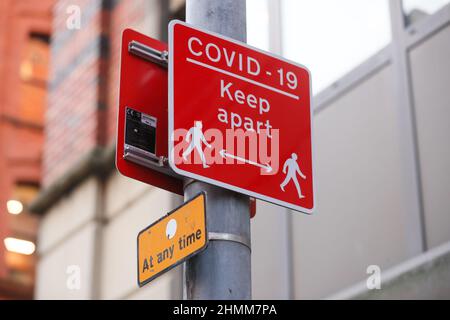 Straßenschilder, um zu versuchen, die Ausbreitung von COVID-19 zu kontrollieren, erinnern die Menschen an soziale Distanz aufgrund der Pandemie. Stockfoto