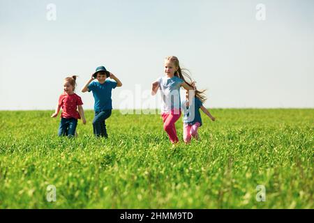 Eine Gruppe von glückliche Kinder von Jungen und Mädchen laufen im Park auf der Wiese an einem sonnigen Sommertag. Das Konzept der ethnischen Freundschaft, Frieden, Freundlichkeit, ch Stockfoto