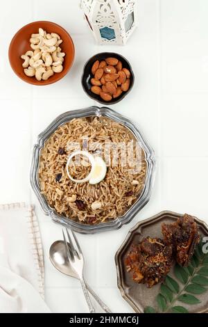 Arabisches traditionelles rustikales Reisgericht Pilaf gekocht mit gebratenen Rippen Fleisch, Zwiebeln, Raisin und Knoblauch auf weißem Holzhintergrund Tisch Stockfoto