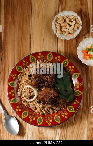 Köstlicher asiatischer Pilaf mit würzigen Lammrippen auf einem roten marokkanischen Teller. Vertikale Ansicht von oben, rustikaler Stil Stockfoto