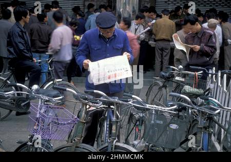 Menschen mit Zeitungen auf dem Aktienmarkt in der Stadt Nanchang in der Provinz Jiangxi in China. China, Nanchang, November 1996 Stockfoto