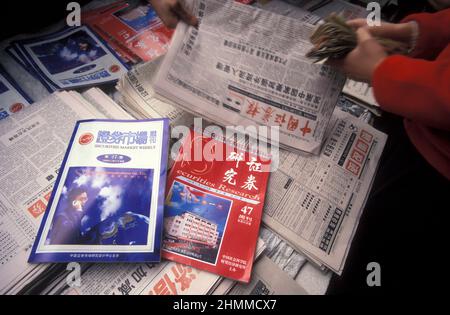 Menschen mit Zeitungen auf dem Aktienmarkt in der Stadt Nanchang in der Provinz Jiangxi in China. China, Nanchang, November 1996 Stockfoto