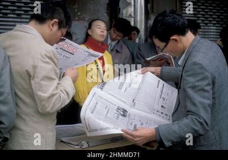 Menschen mit Zeitungen auf dem Aktienmarkt in der Stadt Nanchang in der Provinz Jiangxi in China. China, Nanchang, November 1996 Stockfoto