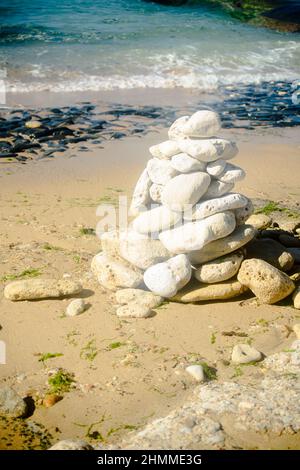 Steinhaufen am Strand auf dem Leuchtturm Phare Des Baleines auf der Insel Ile de Ré in Frankreich an einem sonnigen Sommertag Stockfoto