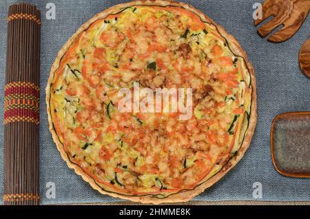 Gesunde vegetarische Mahlzeit. Vegetarische herzhafte Pie auf rustikalem Holztisch. Holzbesteck und ethnische Tischdecke. Stockfoto