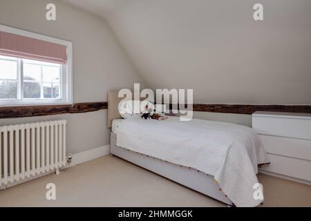 Great Chesterford, Essex - April 3 2017 - Schlafzimmer innen mit freiliegenden Holzbalken, Einzelbett und traditionellen alten Heizkörper in der Zeit zu Hause Stockfoto