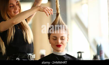 Eine Friseurin hält einen Pferdeschwanz und eine Schere für den Kunden Stockfoto