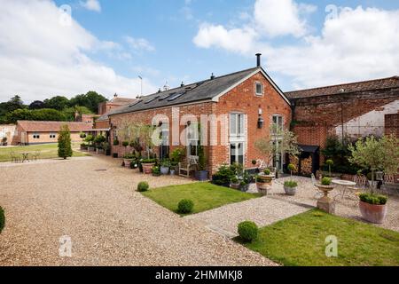 Newport, Essex - Juli 10 2018: Alte Farm Nebengebäude umgewandelt in luxuriöses Landhaus auf dem Land in charmanten Landschaftsgärten Stockfoto