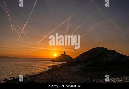 Swansea, Großbritannien. 11th. Februar 2022. Die Sonne geht heute Morgen über dem Leuchtturm im Dorf Mumbles, Swansea, auf. Quelle: Phil Rees/Alamy Live News Stockfoto