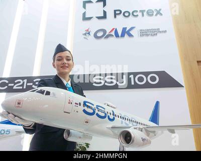 Moskau, Russland. 09th. Februar 2022. Eine Stewardess hält ein Modell des Sukhoi Superjet 100 (SSJ 100) Regionaljet auf der National Aviation Infrastructure Show (NAIS) 9th.NAIS Forum & Show ist die Branchenveranstaltung in Russland und der GUS für Profis von Reiserouten und Infrastruktur der zivilen Luftfahrt: Flughäfen, Flugplätze, Hubschrauberzentren, Fluggesellschaften und andere Fluggesellschaften. Kredit: SOPA Images Limited/Alamy Live Nachrichten Stockfoto