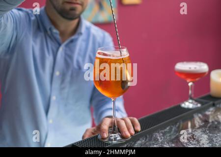 Der Barkeeper macht Aperol Spritz Sommercocktail in Mister Glas. Nahaufnahme Foto, Prozess, Balken. Hochwertige Fotos Stockfoto
