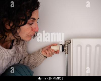 Nijmegen, Niederlande. 10th. Februar 2022. Zu Hause wird eine Frau gesehen, wie sie die Heizung herunterdreht.der Warm Sweater Day wird jedes Jahr an einem Freitag im Februar vom Klimaatverbond Nederland (Climate Association Netherlands) organisiert, einem Zusammenschluss öffentlicher Organisationen mit Ambitionen im Bereich Nachhaltigkeit und Klimawandel. Es handelt sich um eine nationale Klimaschutzmaßnahme, bei der alle Teilnehmer versprechen, die Heizung in ihren Häusern, Büros, am Arbeitsplatz oder in ihren Klassenzimmern zu senken. Anstatt den Raum zu erhitzen, heizen sie sich selbst auf, indem sie einen bequemen, gemütlichen und warmen Swea tragen Stockfoto