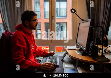 Nijmegen, Niederlande. 10th. Februar 2022. Ein Mann wird zu Hause arbeiten sehen, während er einen gemütlichen Pullover trägt, nachdem er die Heizung heruntergedreht hat.der Warm Sweater Day wird jedes Jahr an einem Freitag im Februar vom Klimaatverbond Nederland (Climate Association Netherlands) organisiert. Das ist ein Zusammenschluss öffentlicher Organisationen mit Ambitionen im Bereich Nachhaltigkeit und Klimawandel. Es handelt sich um eine nationale Klimaschutzmaßnahme, bei der alle Teilnehmer versprechen, die Heizung in ihren Häusern, Büros, am Arbeitsplatz oder in ihren Klassenzimmern zu senken. Statt den Raum zu erhitzen, heizen sie sich selbst auf Stockfoto