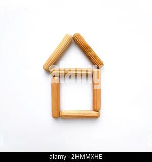 Haus aus Holzstäben auf weißem Hintergrund. Einfache Form Stockfoto