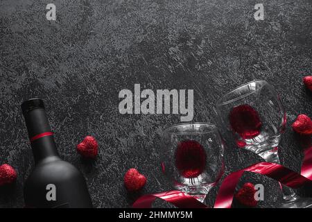 Flasche Wein, rotes Band und Gläser mit Rotwein-Valentinstag Romantik-Konzept mit Platz für Text auf dunklem Hintergrund Stockfoto