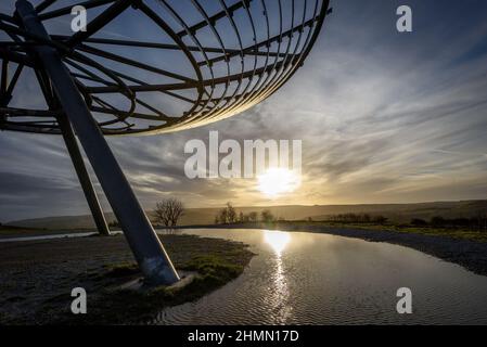 Haslingden, Lancashire, Großbritannien, Mittwoch, 09. Februar 2022. Ein Spaziergänger hält an, um die untergehende Sonne am Halo panopticon über der Stadt Haslingden zu bewundern, Stockfoto