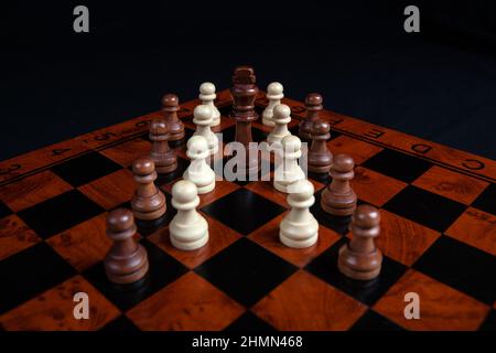 Schachfiguren und König auf einem Brett auf schwarzem Hintergrund aus nächster Nähe Stockfoto