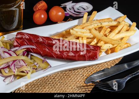 Geräucherte Würstchen mit pommes Frites und Gurken. Snack für Bier. Dunkler Hintergrund. Kopierbereich. Stockfoto