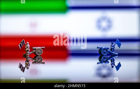 Konzeptuelles Bild des Krieges zwischen Israel und dem Iran mit Spielzeugsoldaten und Nationalflaggen auf einem reflektierenden Hintergrund Stockfoto