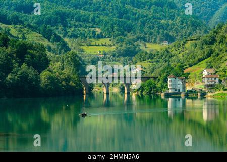 Erstaunliche Landschaft Blick auf den See von Booten, alte Brücke und schöne grüne Berge Hintergrund in Bosnien und Herzegowina Stockfoto