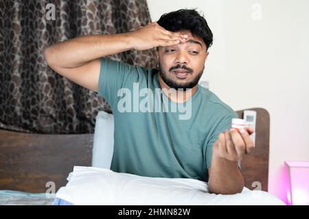 Der junge Mann erhielt nach dem Auftragen von Balsam oder Salbe auf die Stirn aufgrund von Kopfschmerzen oder Migräne während des Schlafens in der Nacht eine Erleichterung - Konzept der Schmerzlinderung Stockfoto