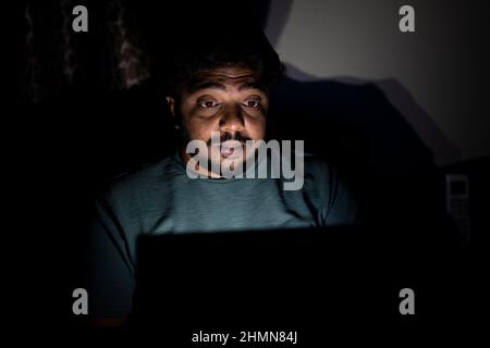 Junge Unternehmensangestellte arbeiten spät in der Nacht mit dem Laptop im Schlafzimmer - Konzept der Nachtarbeit, gestresst und Arbeit von zu Hause aus Stockfoto