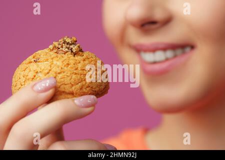 Nahaufnahme Porträt von schönen Mädchen hält in Händen Kuchen isoliert über rosa Pastell Hintergrund Stockfoto