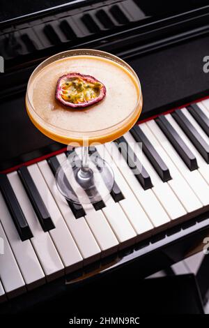 Pornstar Martini Cocktail garniert mit einer Hälfte einer Passionsfrucht auf einer Klaviertastatur Stockfoto
