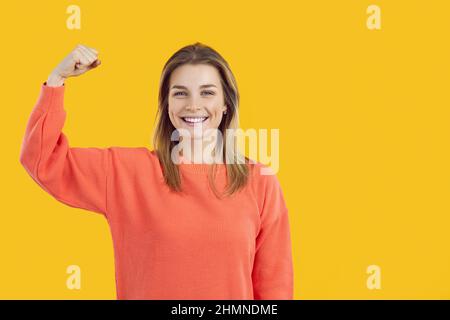 Glückliche selbstbewusste Frau lächelt und beugte ihren Arm, um zu zeigen, dass sie Supermacht hat Stockfoto