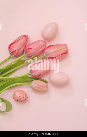 Frohe Ostern Grußkarte. Pastellfarbe Ei und Tulpe Blumenstrauß auf rosa Hintergrund, Draufsicht, kopieren Raum. Frühlingsfeiertage Stockfoto