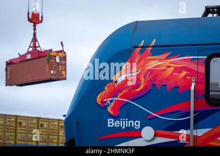 Mukran, Deutschland. 11th. Februar 2022. Hinter einer Lokomotive mit asiatischem Drachenkopf und der Aufschrift 'Beijing' wird nach der Ankunft des ersten Schiffes einer neuen 'Seidenstraße'-Verbindung zwischen China und Deutschland im Hafen von Mukran ein Container entladen. Die Container aus dem chinesischen Wuhan decken einen Teil der Strecke auf dem Wasser ab und werden auf der Insel Rügen auf Schienenfahrzeuge verladen. Quelle: Jens Büttner/dpa-Zentralbild/dpa/Alamy Live News Stockfoto