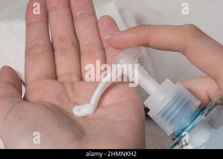 Frau hält die Cremeböhre und wendet Feuchtigkeitscreme auf ihre schönen Hände an, um eine saubere und weiche Haut zu erhalten. Weißer Hintergrund. Achten Sie auf Ihre Körperhaut. Stockfoto