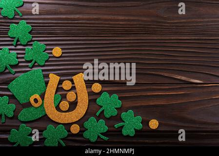 Handgefertigter dreiblättriger Shamrock-Hufeisenhut aus Filz und Münzen auf Holzhintergrund Stockfoto