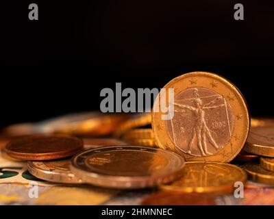 Rückseite der 1-Euro-2002-Münze, die Italien gewidmet ist, unter verschiedenen Münzen auf schwarzem Hintergrund Stockfoto