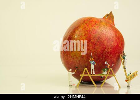 Ein Team von Malern mit einer Leiter und Holzgerüst arbeiten an einem Granatapfel, Stockfoto